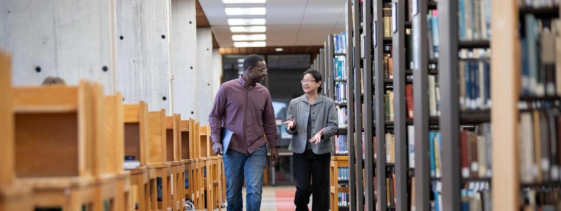 鶹ƵAPK Student and Professor walking in Bush library